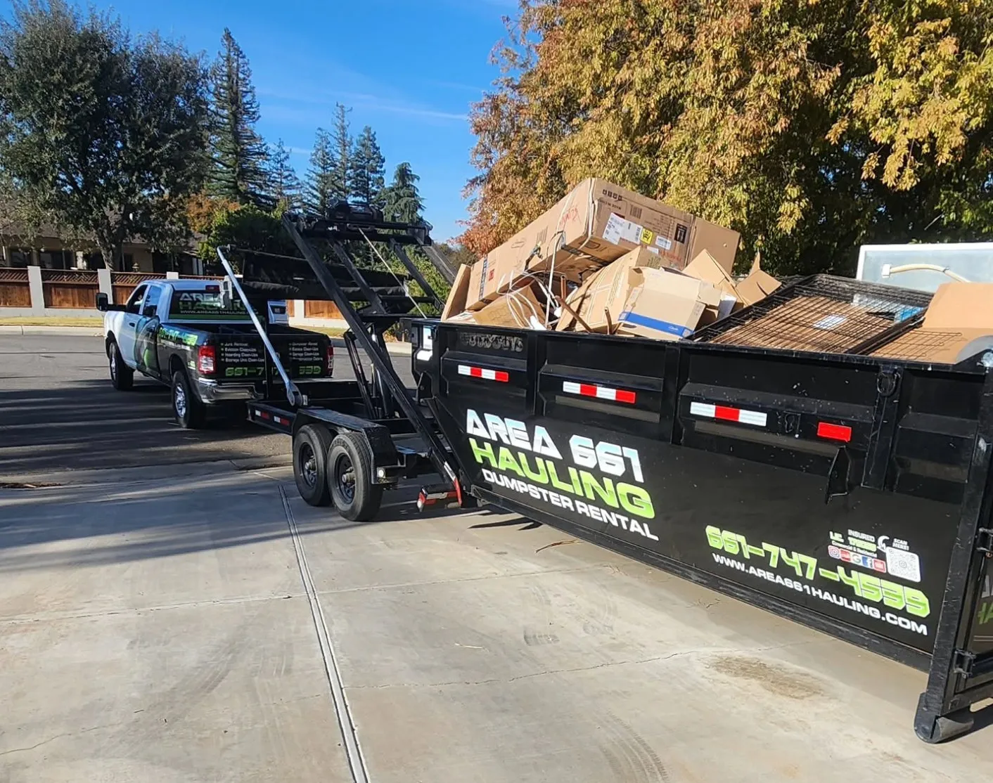 An Area 661 Hauling roll-off dumpster loaded with flattened cardboard and construction debris on a Bakersfield driveway.