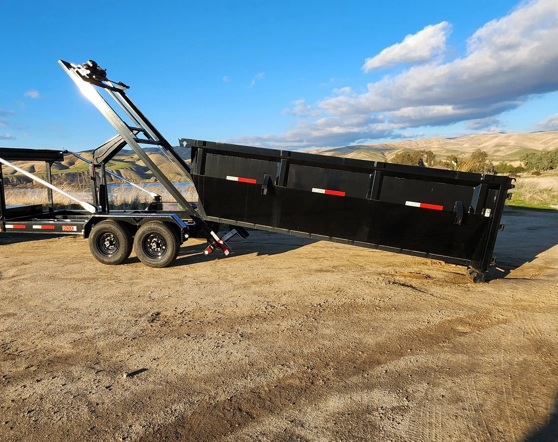 An Area 661 Hauling dumpster trailer tipped up to unload on an open lot outside Bakersfield.