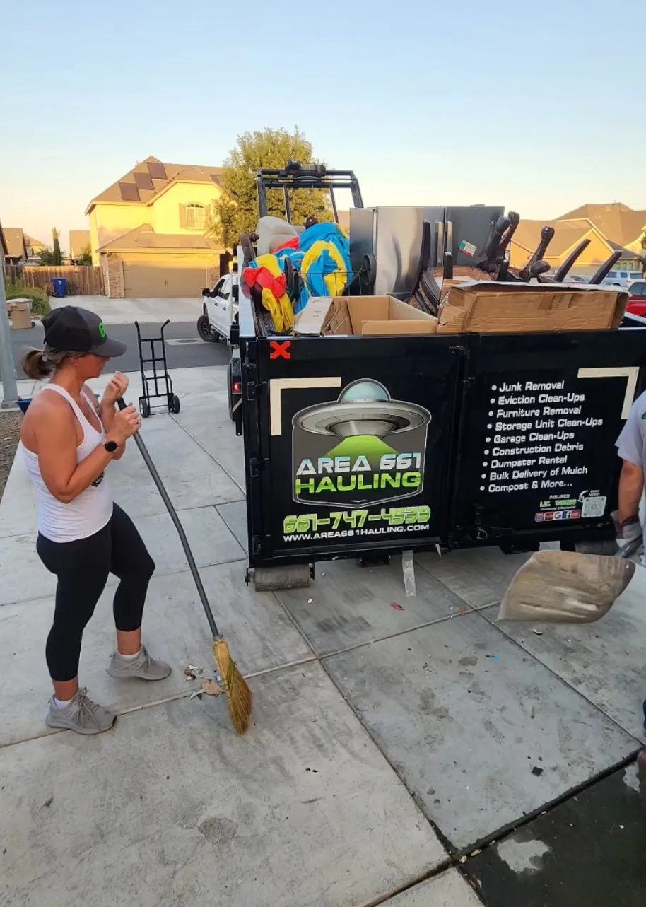 A woman is standing next to a dumpster that says Area 661 Hauling.