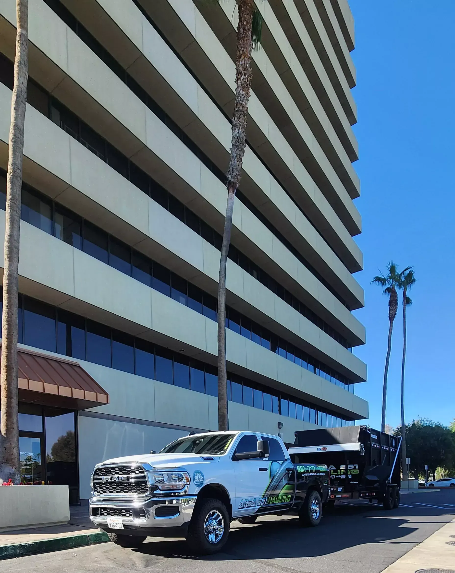 An Area 661 Hauling truck and dump trailer parked on the street outside a Bakersfield office building.