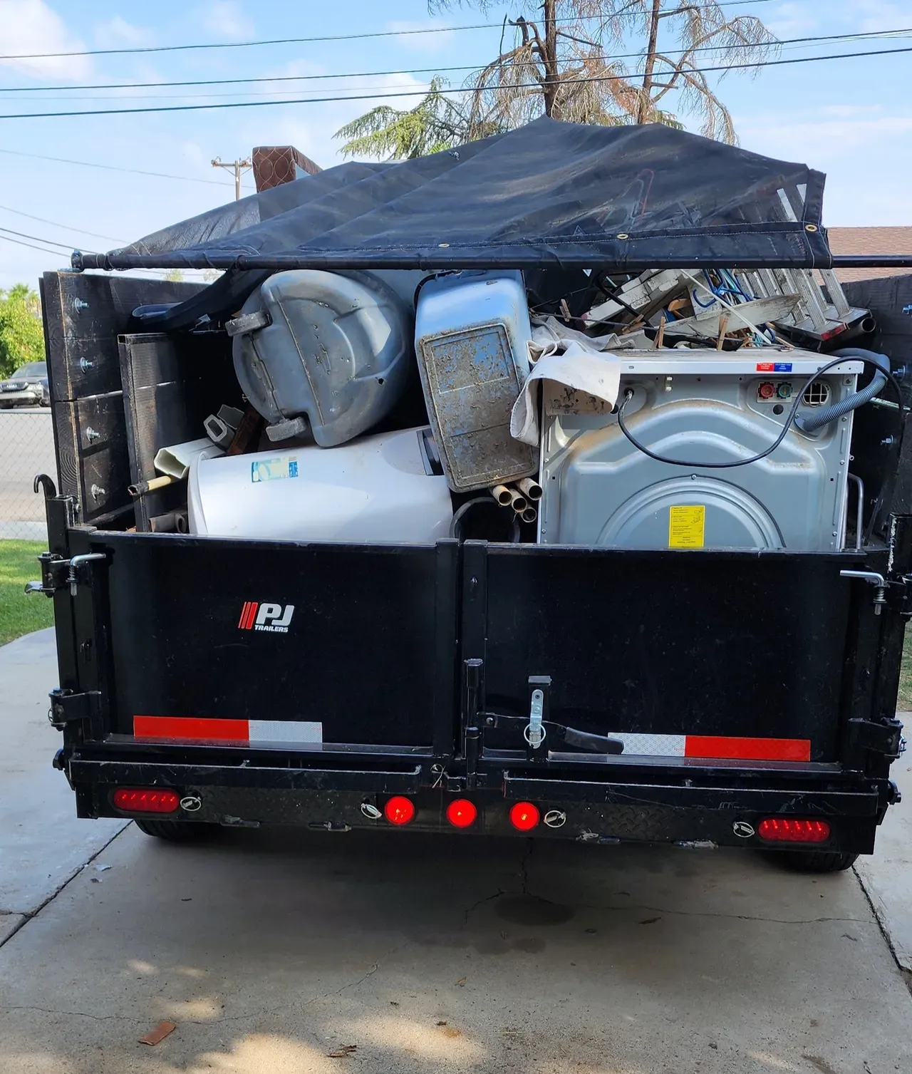 A dumpster with a washer and dryer in it being hauled away